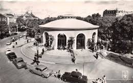 Carte photo ancienne en noir et blanc d'un pavillon de source circulaire de Vichy, entouré d'automobiles d'époque